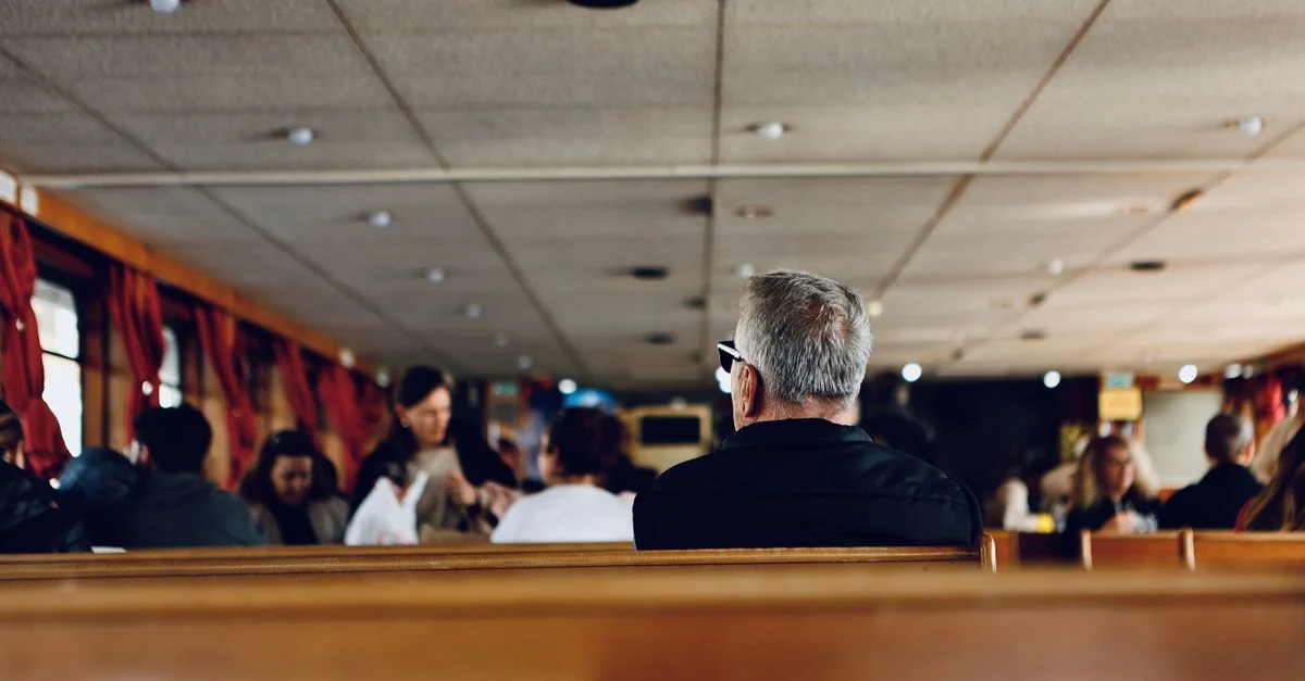 Les passagers se détendent sur un ferry confortable avec des bancs en bois et des rideaux rouges.