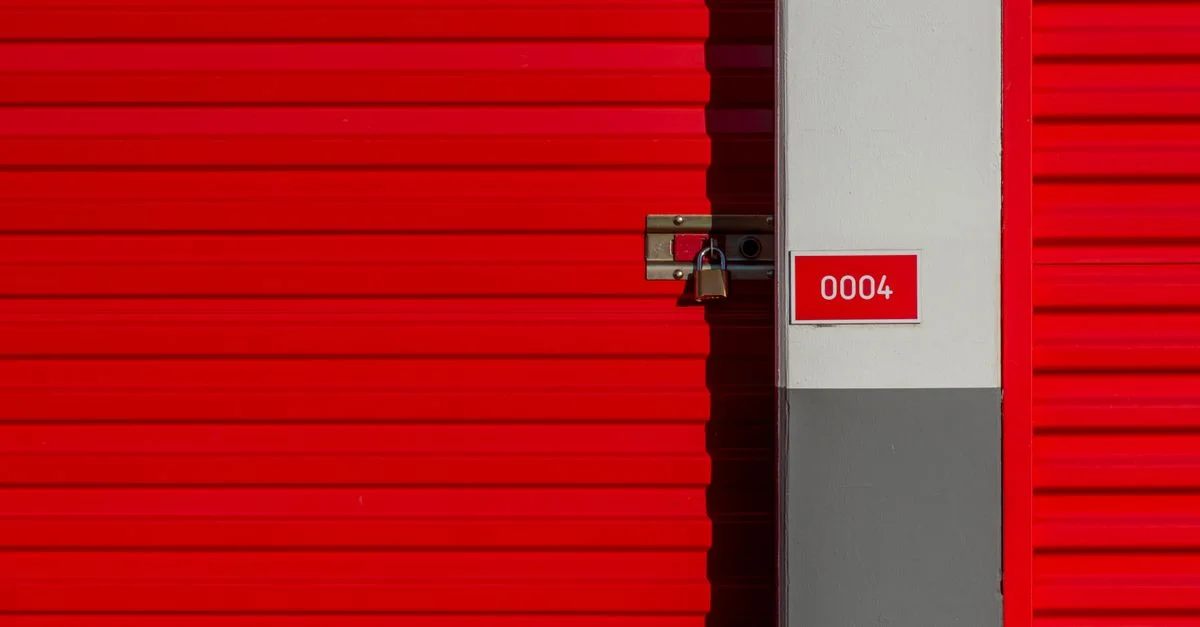 Porte d'unité de stockage en métal rouge avec cadenas et panneau blanc affichant le numéro 0004.