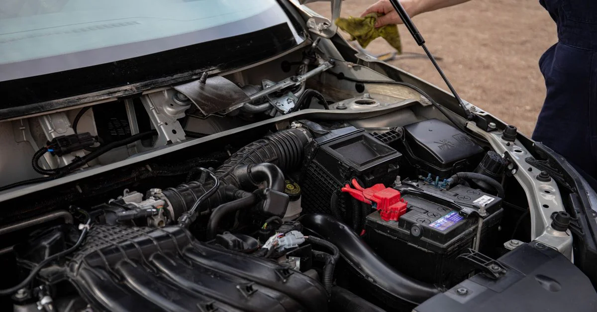 Mécanicien inspectant le compartiment moteur et la batterie lors de l'entretien de routine.