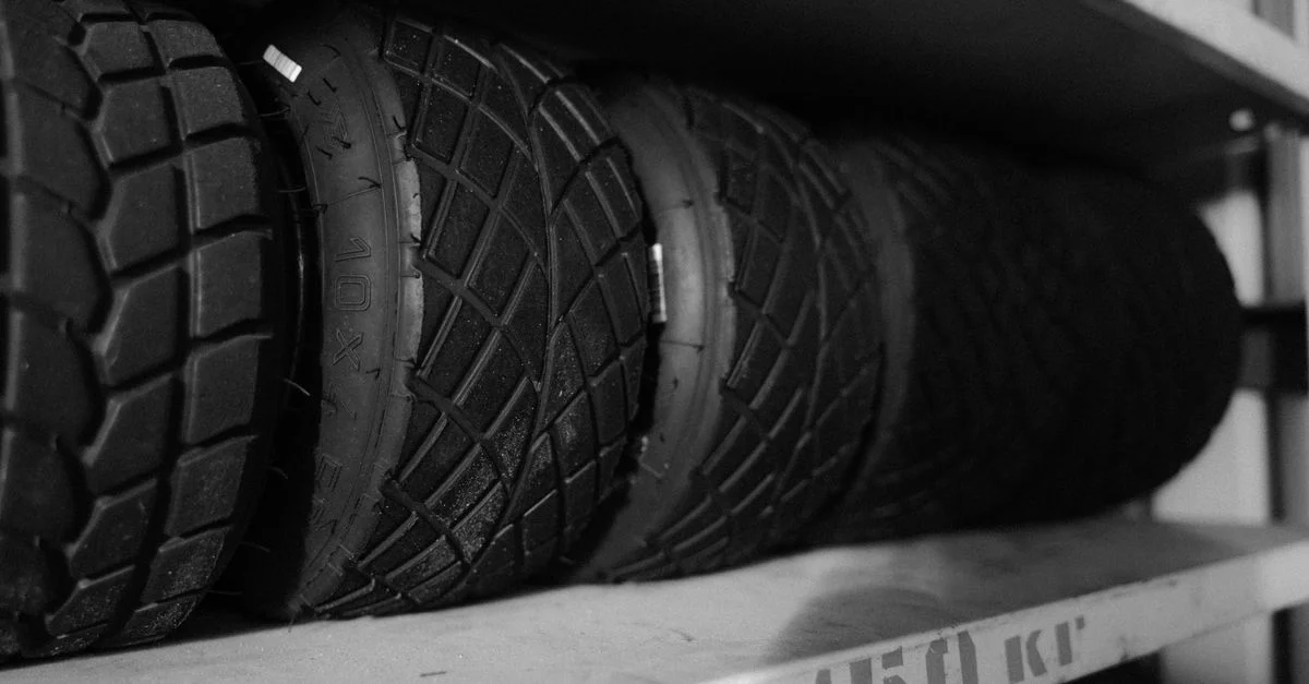 Photo monochrome de plusieurs pneus soigneusement disposés sur une étagère en gros plan.