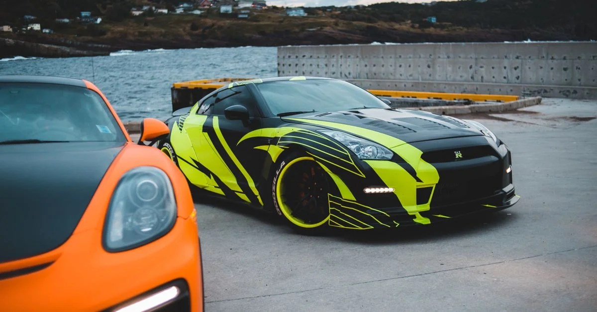 Image époustouflante de voitures de sport de luxe garées au bord de la mer au crépuscule, avec des designs vibrants en vert et orange.