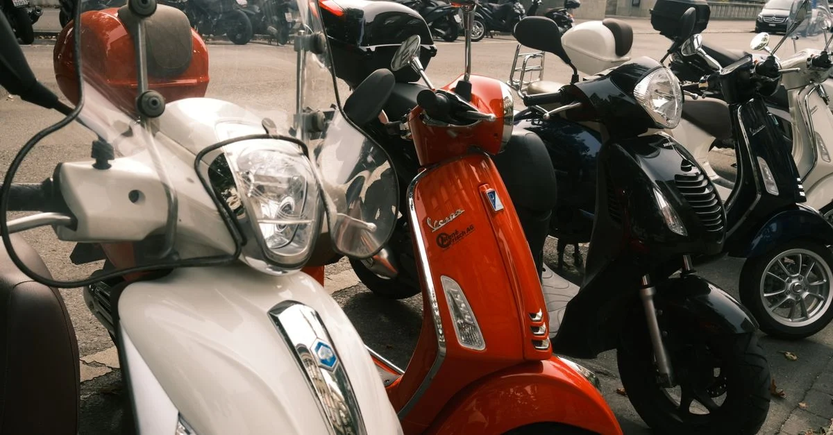 Une rangée de scooters aux couleurs vives, garés en extérieur dans une zone urbaine, illustre un design moderne.