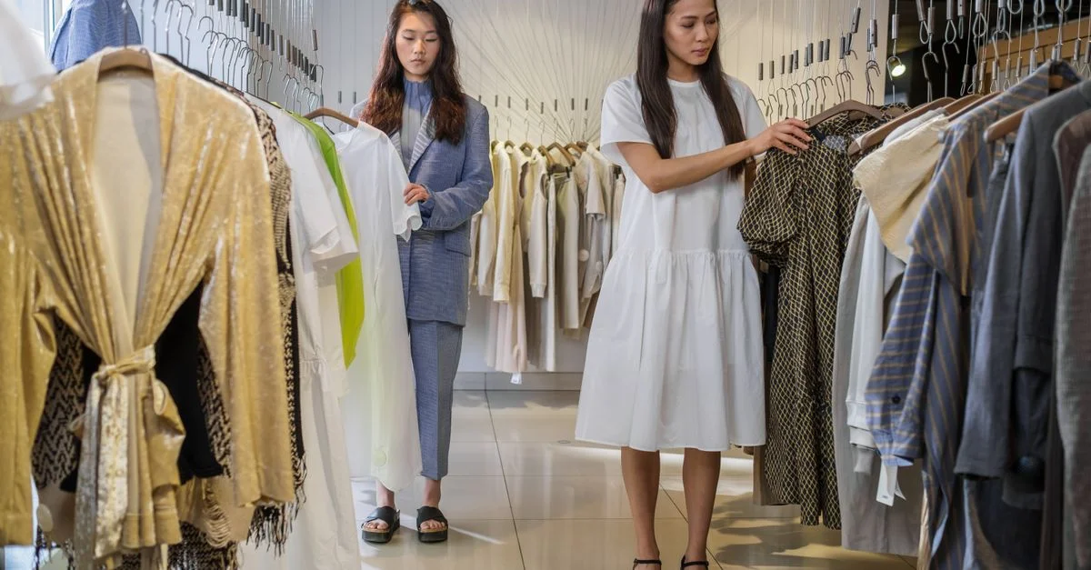 Deux femmes parcourant des vêtements tendance dans une boutique moderne.