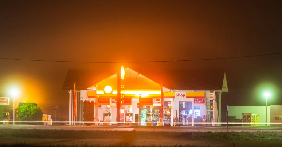 Une station-service bien éclairée enveloppée de brume la nuit, créant une lueur vibrante.