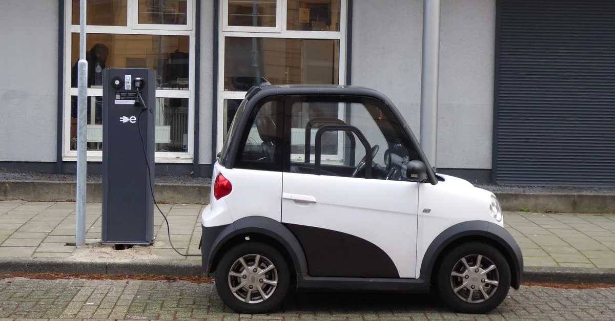 Une voiture électrique compacte blanche et noire se recharge à une station de puissance publique.