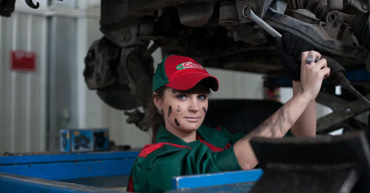 Mécanicienne entretennant une voiture dans un garage, montrant compétence et concentration.