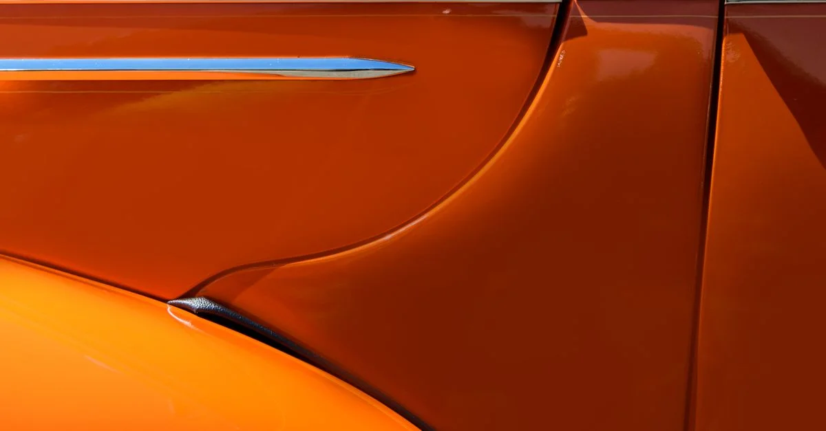 Gros plan détaillé d'une voiture vintage orange brillante avec des accents en chrome.